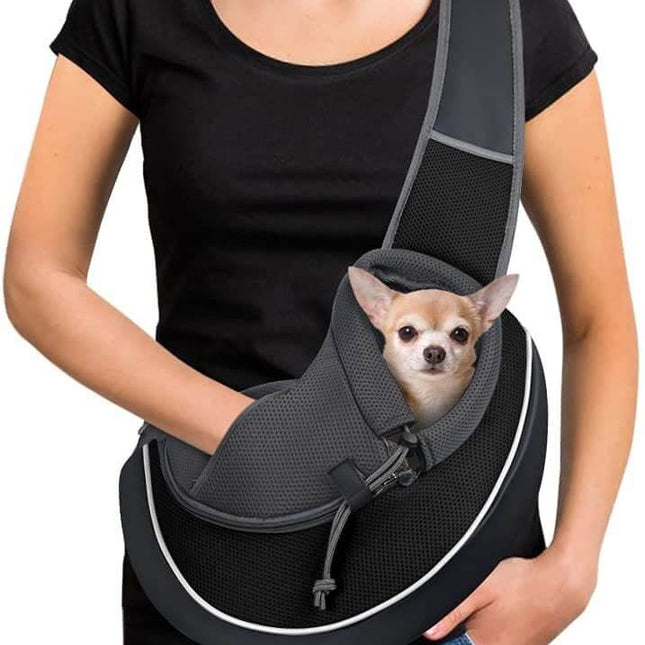 Person holding a small dog in a black pet sling carrier.